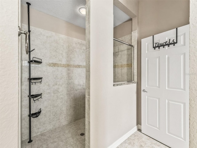 bathroom featuring tiled shower, tile patterned floors, and a textured ceiling