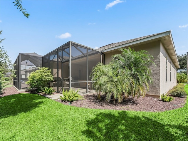 rear view of house featuring a patio, glass enclosure, and a lawn