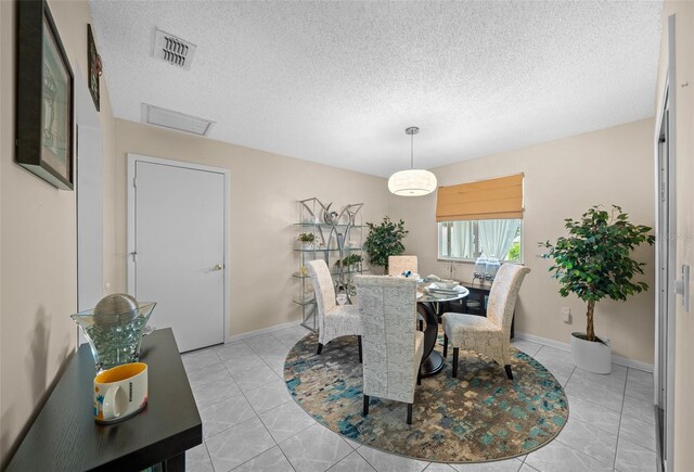 dining room featuring baseboards, a textured ceiling, visible vents, and light tile patterned floors