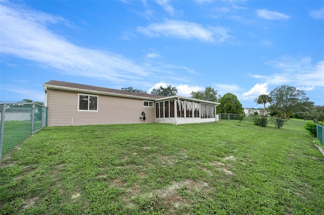rear view of house featuring a yard, a fenced backyard, and a sunroom
