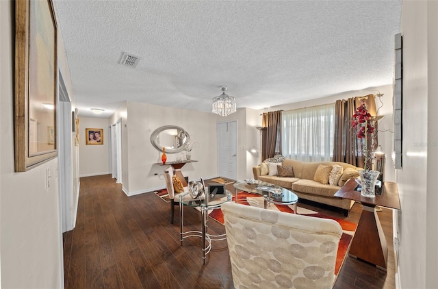 living room featuring dark wood-type flooring, a textured ceiling, and an inviting chandelier