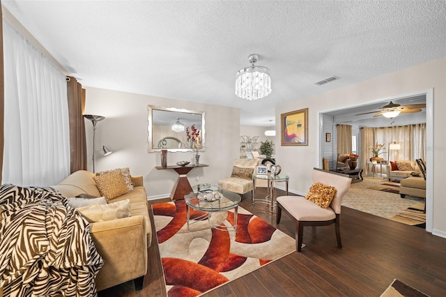 living room with hardwood / wood-style floors, ceiling fan with notable chandelier, and a textured ceiling