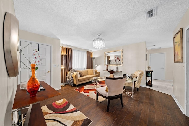 living room with hardwood / wood-style floors, a notable chandelier, and a textured ceiling