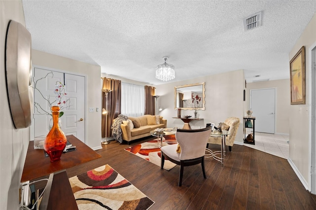 living room featuring an inviting chandelier, baseboards, wood finished floors, and visible vents