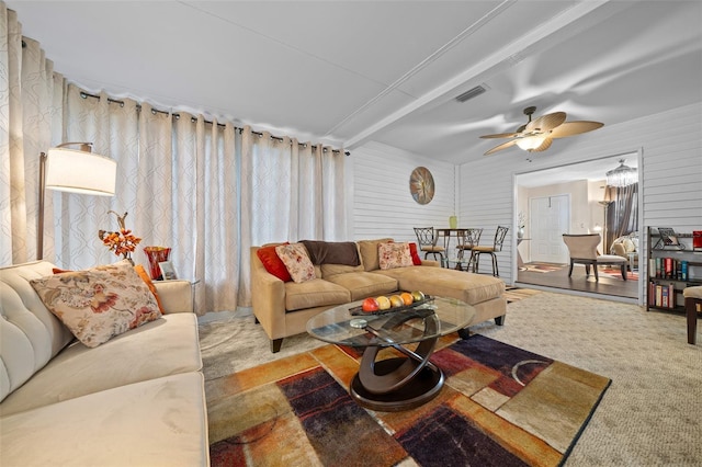 living room featuring carpet, ceiling fan, beamed ceiling, and wooden walls