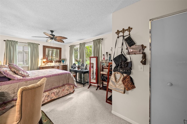 carpeted bedroom featuring ceiling fan and a textured ceiling