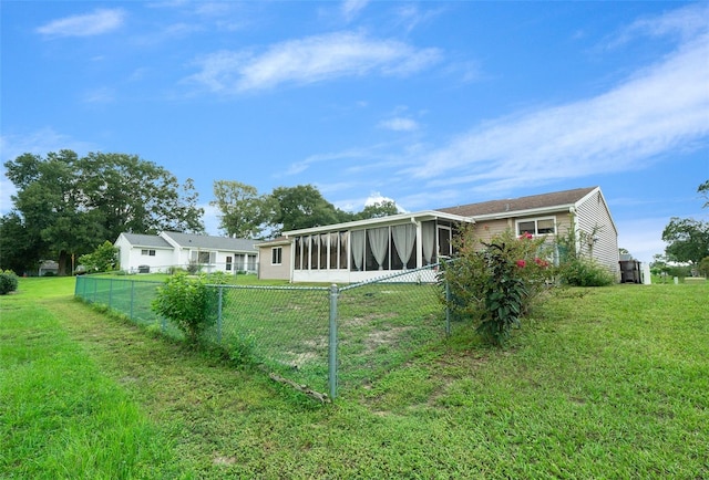 rear view of house featuring a lawn, fence private yard, and a sunroom