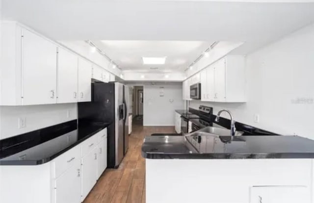 kitchen featuring wood-type flooring, stainless steel appliances, sink, and white cabinetry