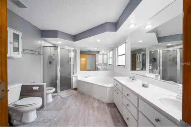 full bathroom with plus walk in shower, a textured ceiling, vanity, and toilet