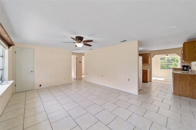 unfurnished living room with light tile patterned floors, sink, and ceiling fan