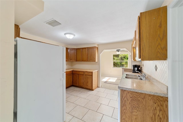 kitchen featuring light tile patterned flooring, sink, ceiling fan, and white fridge