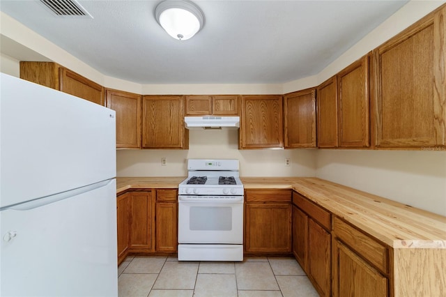 kitchen with light tile patterned flooring, white appliances, and wood counters