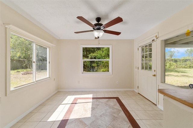 interior space featuring a wealth of natural light, ceiling fan, light tile patterned floors, and a textured ceiling