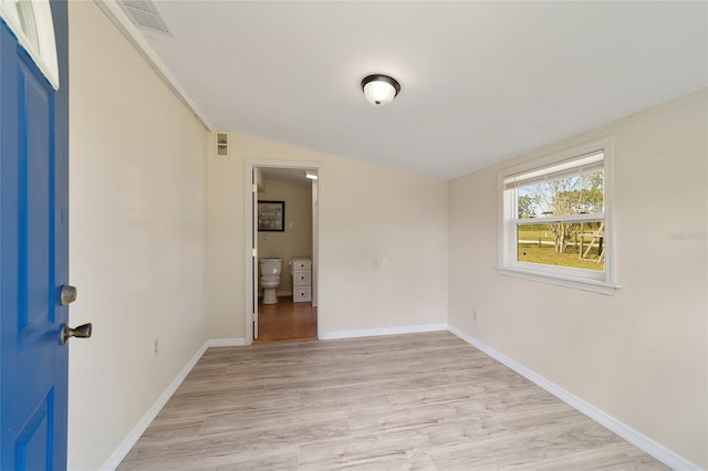 empty room with light wood-type flooring and lofted ceiling