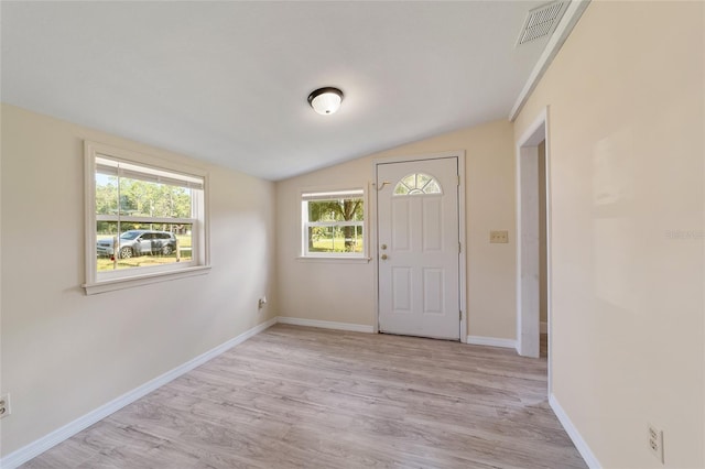 foyer entrance with light wood-type flooring, vaulted ceiling, and a healthy amount of sunlight