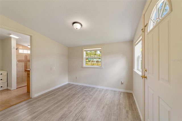 foyer with light wood-type flooring and vaulted ceiling