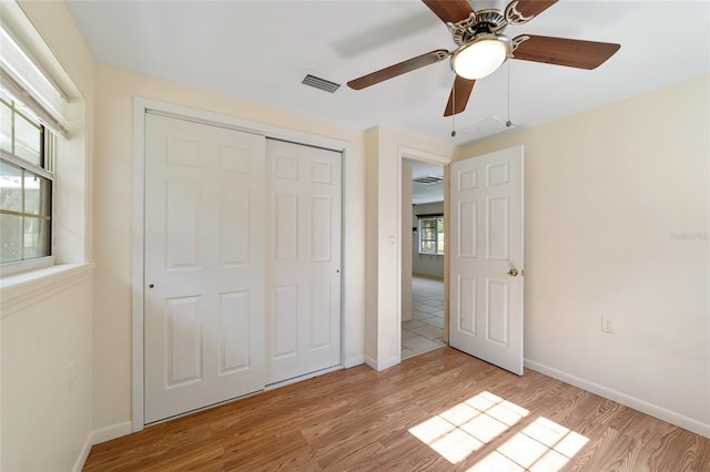 unfurnished bedroom with light wood-type flooring, ceiling fan, and a closet