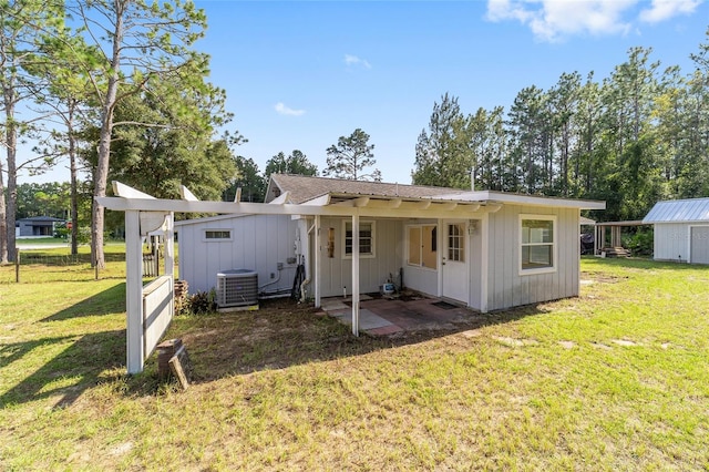 rear view of house with a lawn, a storage shed, central AC, and a patio area