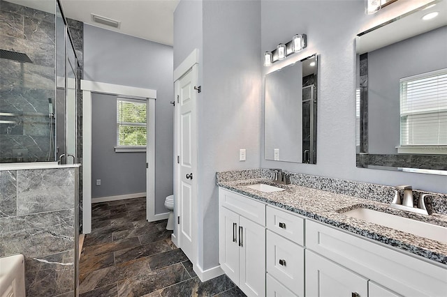 bathroom featuring a shower with shower door, vanity, and toilet