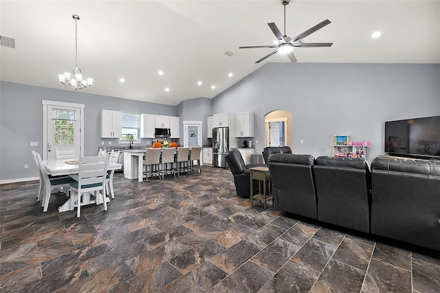 living room featuring high vaulted ceiling, ceiling fan with notable chandelier, and sink