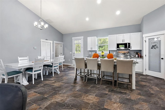 kitchen featuring a center island with sink, white cabinetry, appliances with stainless steel finishes, high vaulted ceiling, and pendant lighting