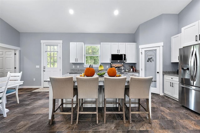 kitchen featuring white cabinetry, stainless steel appliances, a breakfast bar area, and a center island