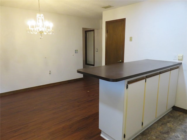 kitchen with pendant lighting, a notable chandelier, white cabinetry, kitchen peninsula, and dark hardwood / wood-style flooring