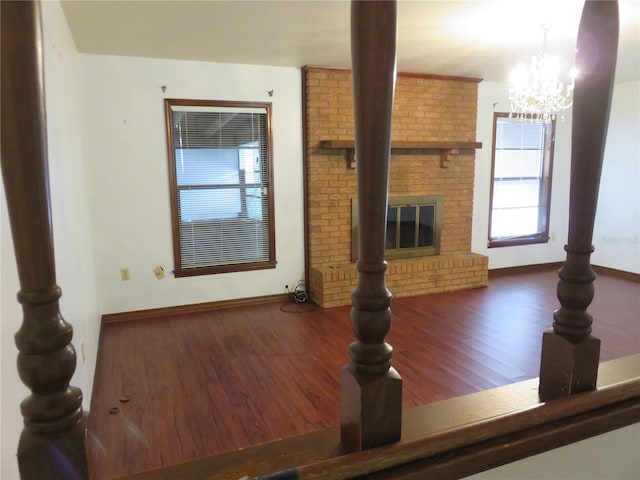 unfurnished living room featuring a fireplace, dark wood-type flooring, and a chandelier