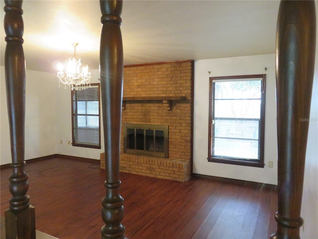 unfurnished living room featuring an inviting chandelier, a fireplace, and dark hardwood / wood-style flooring