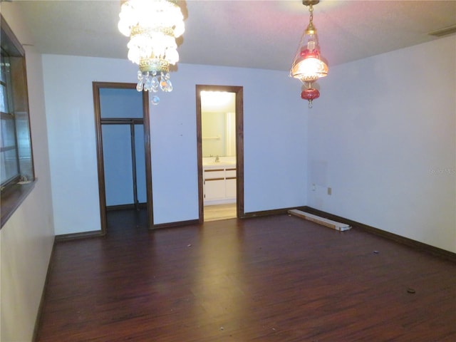 spare room featuring dark hardwood / wood-style floors and a notable chandelier