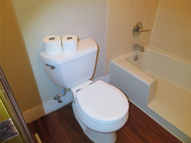 bathroom featuring bathtub / shower combination, wood-type flooring, and toilet