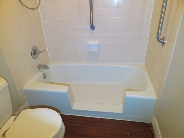 bathroom with hardwood / wood-style floors, tiled shower / bath combo, and toilet