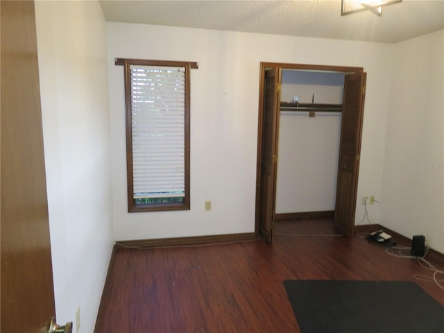 unfurnished bedroom featuring dark wood-type flooring and a closet