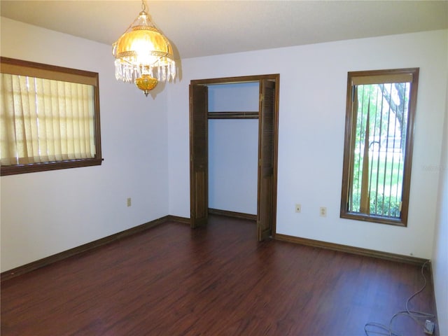 empty room featuring dark hardwood / wood-style floors and a chandelier