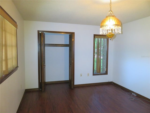 unfurnished bedroom featuring dark hardwood / wood-style floors and a chandelier