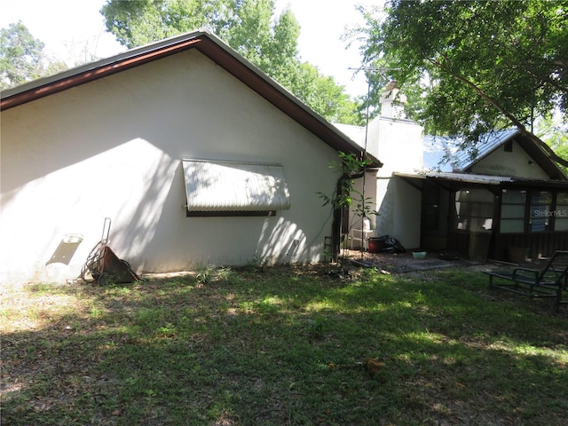 view of property exterior with a sunroom and a yard