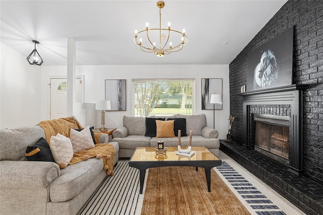 living room with a brick fireplace, a notable chandelier, vaulted ceiling, and light hardwood / wood-style floors