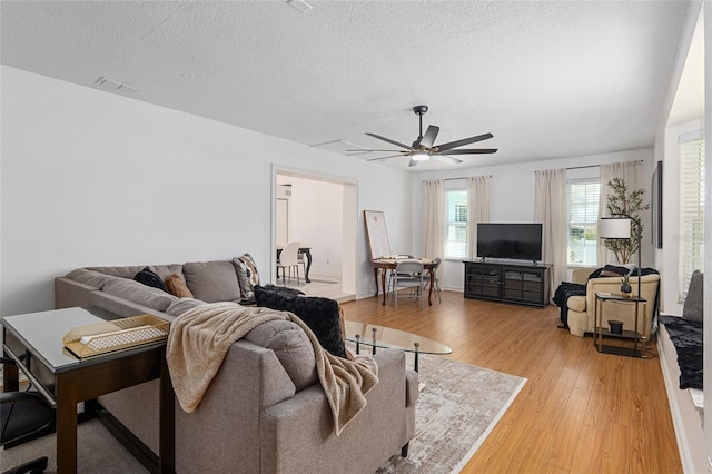 living room featuring ceiling fan, a textured ceiling, and hardwood / wood-style floors