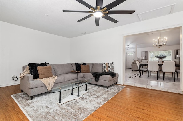 living room featuring ceiling fan with notable chandelier and hardwood / wood-style floors