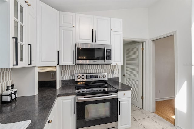 kitchen with light hardwood / wood-style floors, tasteful backsplash, stainless steel appliances, white cabinets, and lofted ceiling