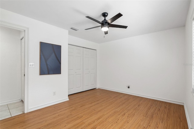 unfurnished bedroom with light wood-type flooring, ceiling fan, and a closet