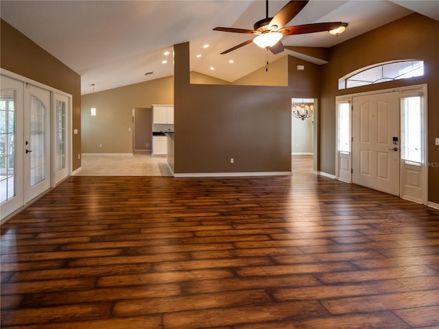 foyer entrance featuring ceiling fan with notable chandelier, dark wood-type flooring, and high vaulted ceiling