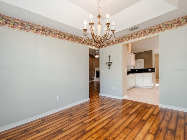 unfurnished room featuring a chandelier and light hardwood / wood-style floors