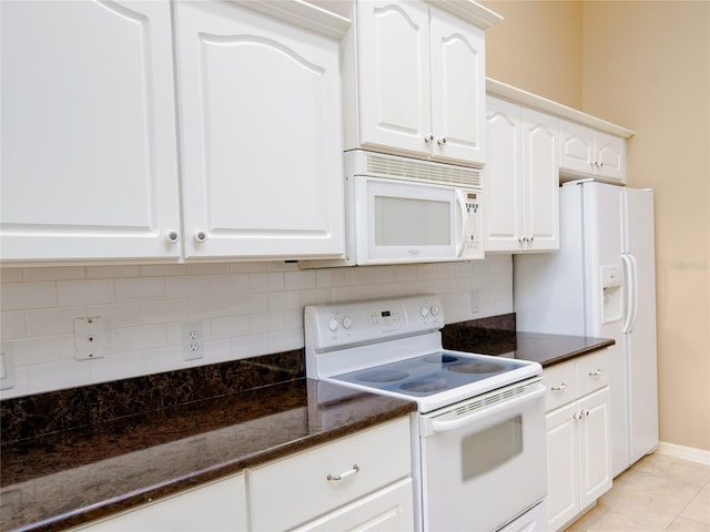 kitchen with tasteful backsplash, white cabinets, white appliances, light tile patterned floors, and dark stone countertops