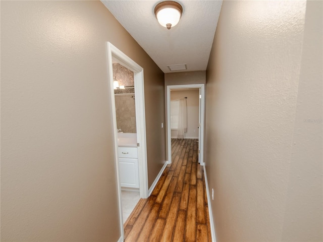 hall with a textured ceiling and dark hardwood / wood-style flooring