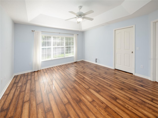 empty room featuring ceiling fan, hardwood / wood-style flooring, and a tray ceiling