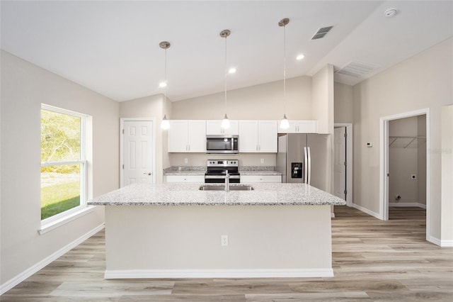 kitchen with decorative light fixtures, a kitchen island with sink, stainless steel appliances, white cabinets, and light stone counters