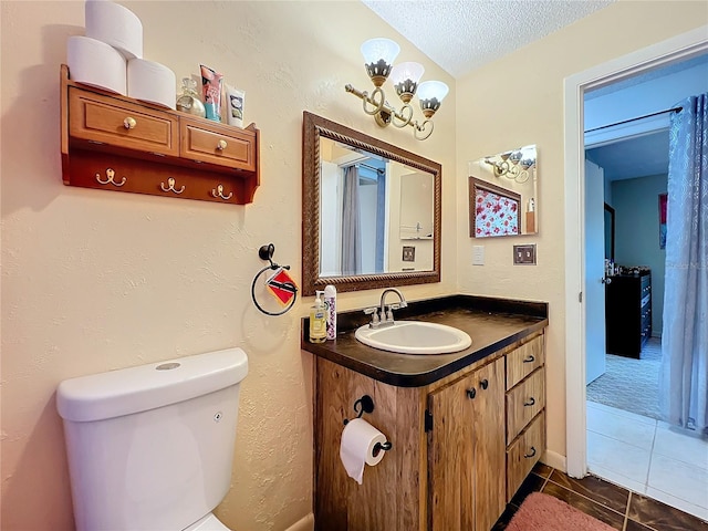 bathroom with a textured ceiling, vanity, toilet, and tile patterned floors