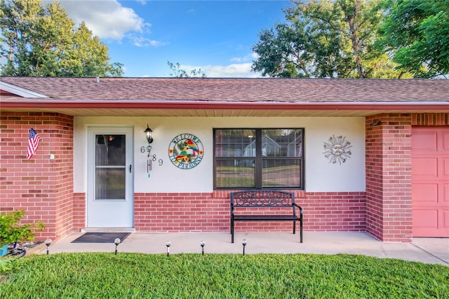 view of exterior entry featuring brick siding and a garage