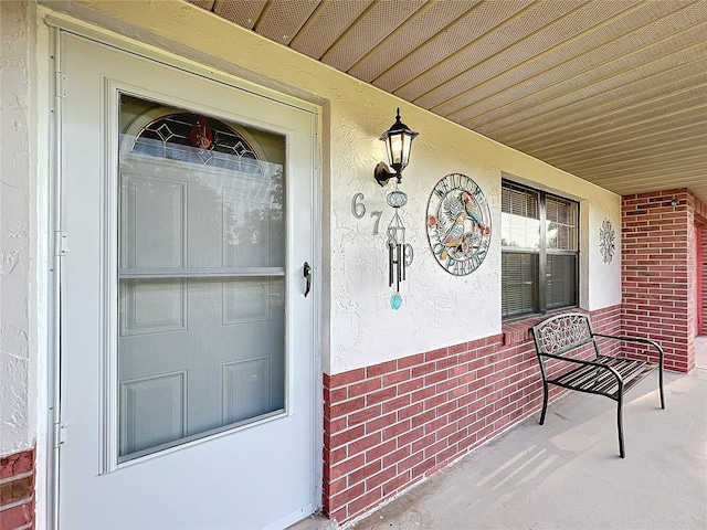 property entrance with covered porch and brick siding